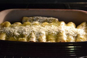Cover enchiladas with tomatillo sauce and remaining shredded cheese. Try to completely cover the tortillas so that they don't become too crispy in the oven. Bake for about 30 minutes until the sauce bubbles and cheese melts.